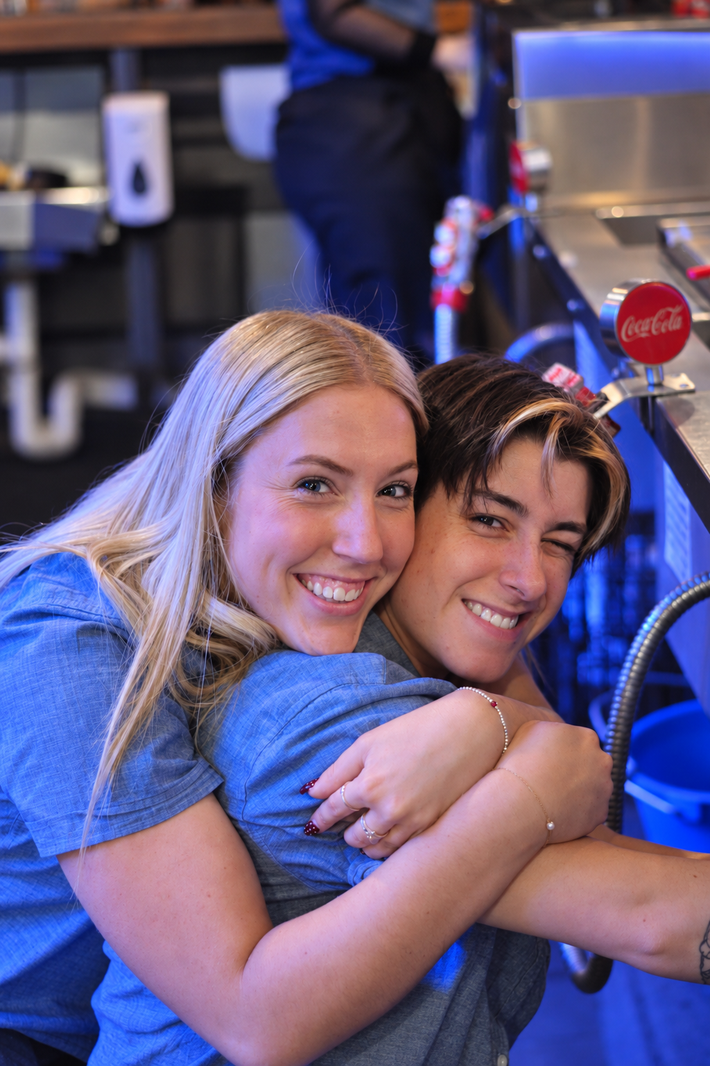 Two friends smiling together behind a bar